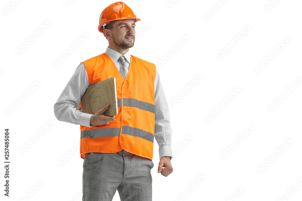 The builder in a construction vest and an orange helmet with laptop. Safety specialist, engineer, industry, architecture, manager, occupation, businessman, job concept The builder in a construction vest and an orange helmet with laptop. Safety specialist, engineer, industry, architecture, manager, occupation, businessman, job concept