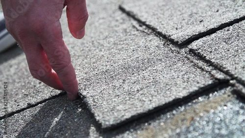 Roofing contractor showing old damaged asphalt shingles at residence