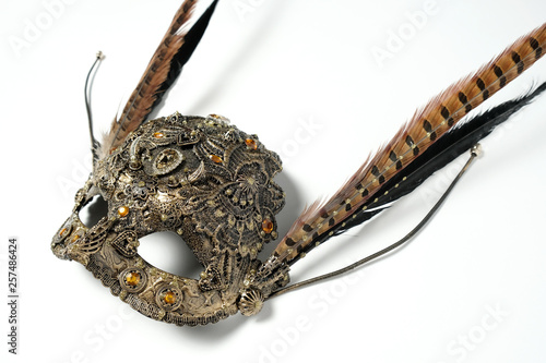 Closeup studio shot of creative metal mask with jewels and feathers isolated on white background