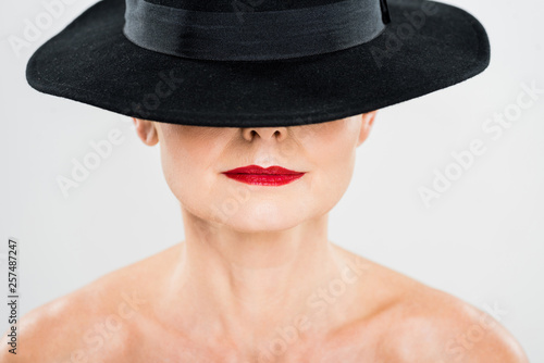 middle aged elegant and fashionable woman with red lips in black hat isolated on grey