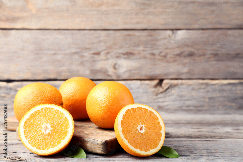 Orange fruit with green leafs and cutting board on grey wooden table Orange fruit with green leafs and cutting board on grey wooden table