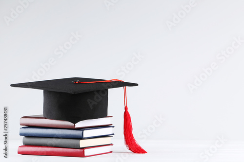 Obraz na płótnie Graduation cap with stack of books on grey background