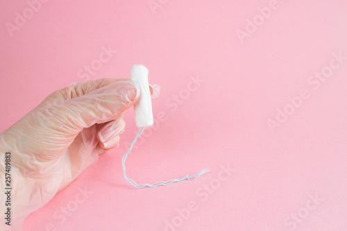 woman hand in medicine glove holding hygienic tampon on pink background