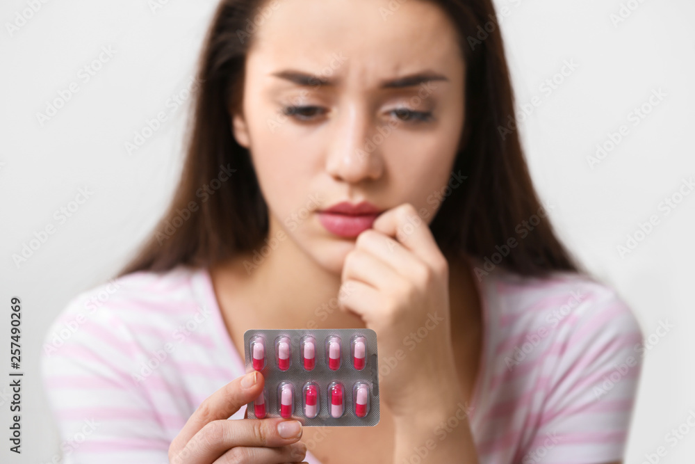 Young woman with pills on light background, closeup Young woman with pills on light background, closeup