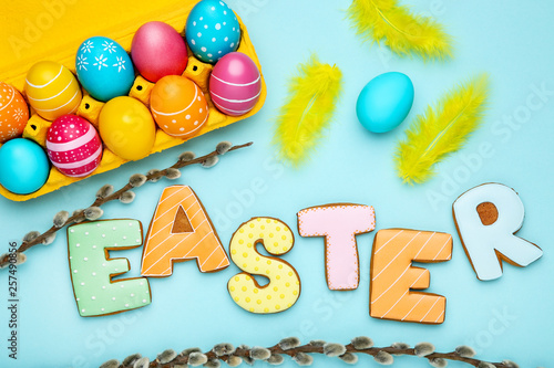 Colorful eggs with word Easter and willow branches on blue background