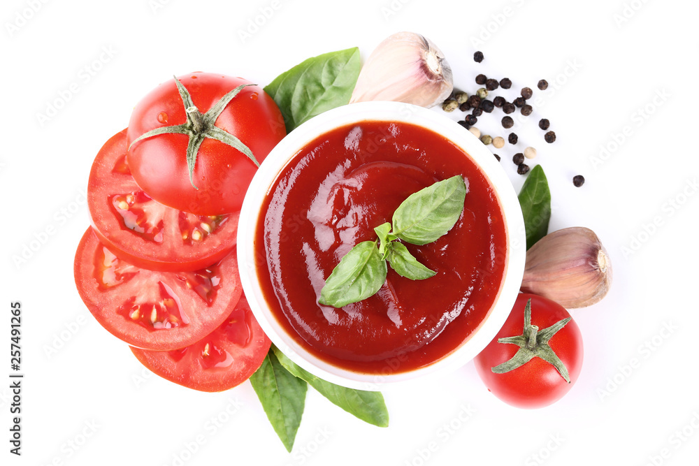 Ketchup in bowl with tomatoes and basil leafs isolated on white background
