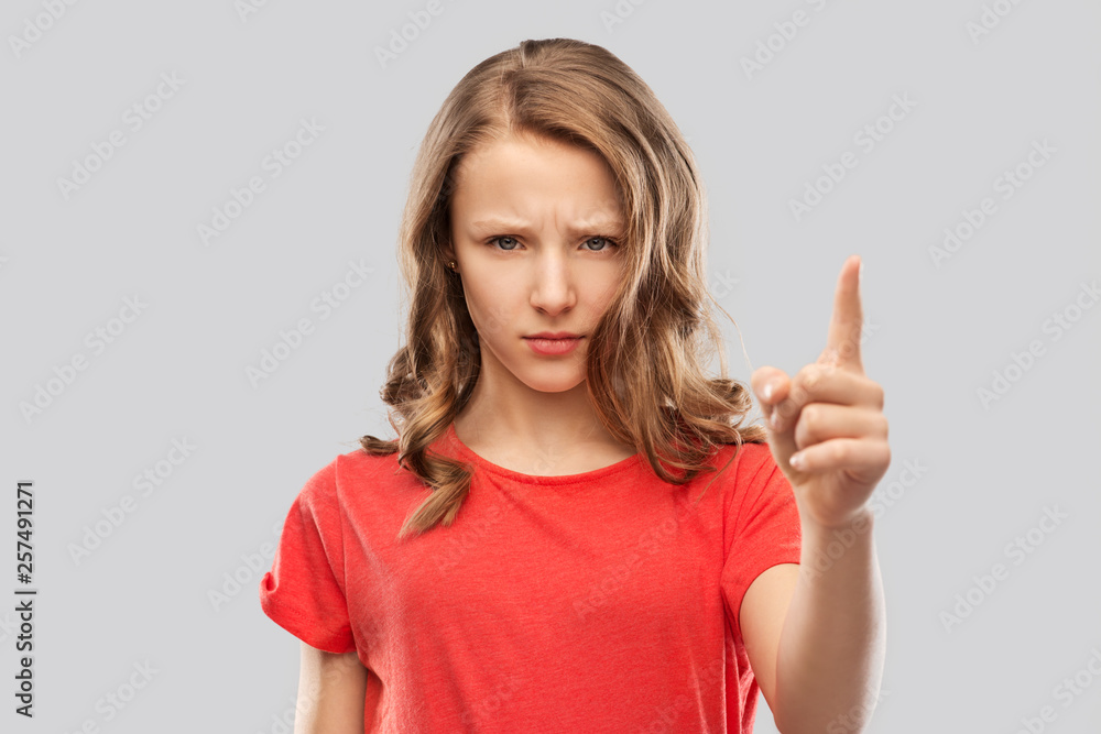 warning, attention and people concept - angry frowning teenage girl pointing finger up over grey background warning, attention and people concept - angry frowning teenage girl pointing finger up over grey background