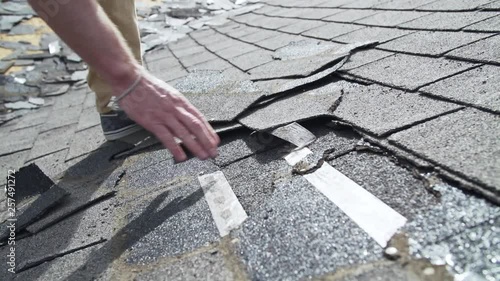 Contractor with damaged old asphalt roof shingles on residential home