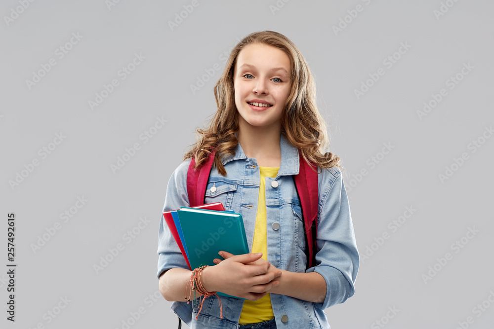 education, school and people concept - happy smiling teenage student girl with bag and books over grey background education, school and people concept - happy smiling teenage student girl with bag and books over grey background
