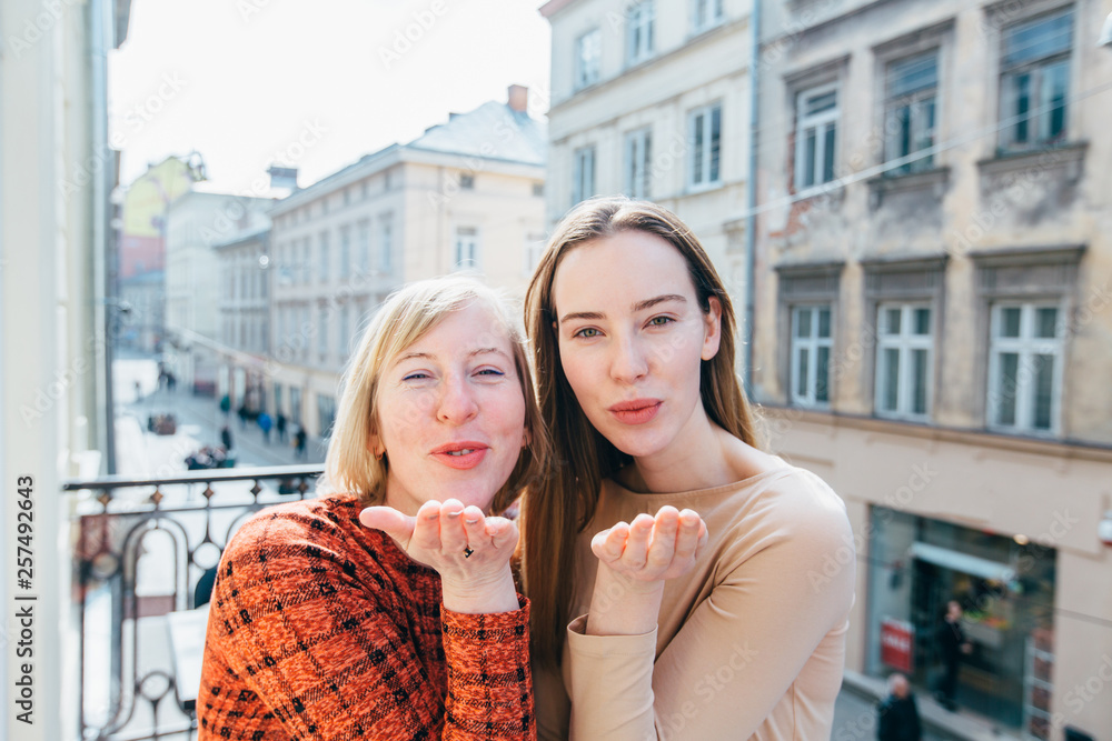 Happy loving family! Beautiful family of middle age mature mother and adult  daughter together looking at the camera blowing a kiss with hand on air  being lovely and sexy. Love expression. Stock