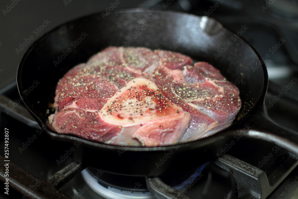 Shank steak frying in a cast iron pan. Shank steak frying in a cast iron pan.