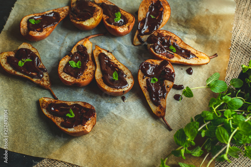 Fototapeta Naklejka Na Ścianę i Meble -  pear baked on butter with cinnamon and sugar spread with hot dark chocolate with the addition of chopped leaves mints