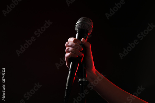 Woman holding microphone on black background, closeup