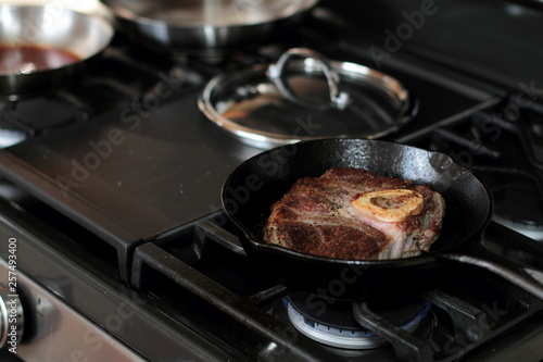 Shank steak frying in a cast iron pan.