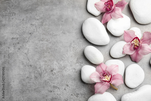 Canvas Print Zen stones and exotic flowers on grey background, top view with space for text