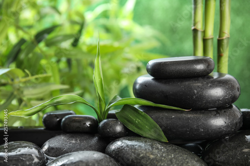 Zen stones and bamboo leaves in water on blurred background. Space for text