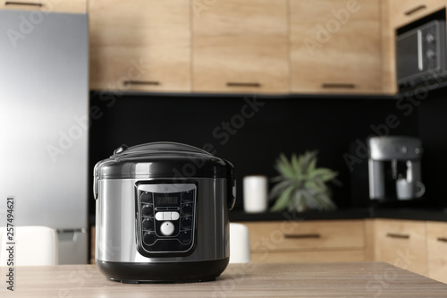 Modern multi cooker on table in kitchen, space for text