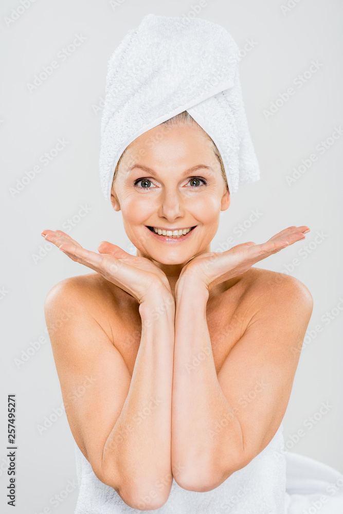 attractive and smiling mature woman in towels looking at camera isolated on grey attractive and smiling mature woman in towels looking at camera isolated on grey