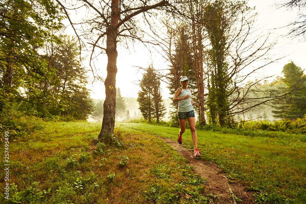 A female trail runner running on singletrack. A female trail runner running on singletrack.