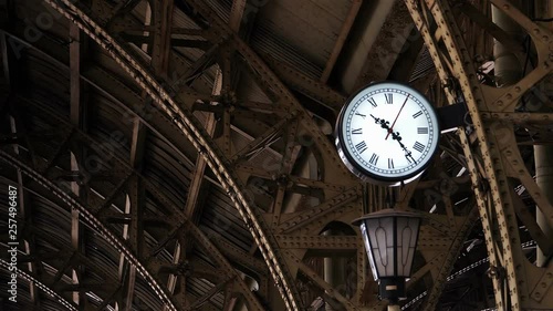 Clock on the old railway station among the metal structures.