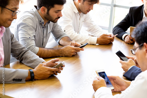Cuadro en lienzo Multi-ethnic and diverse businessmen all using their phone on desk inside office