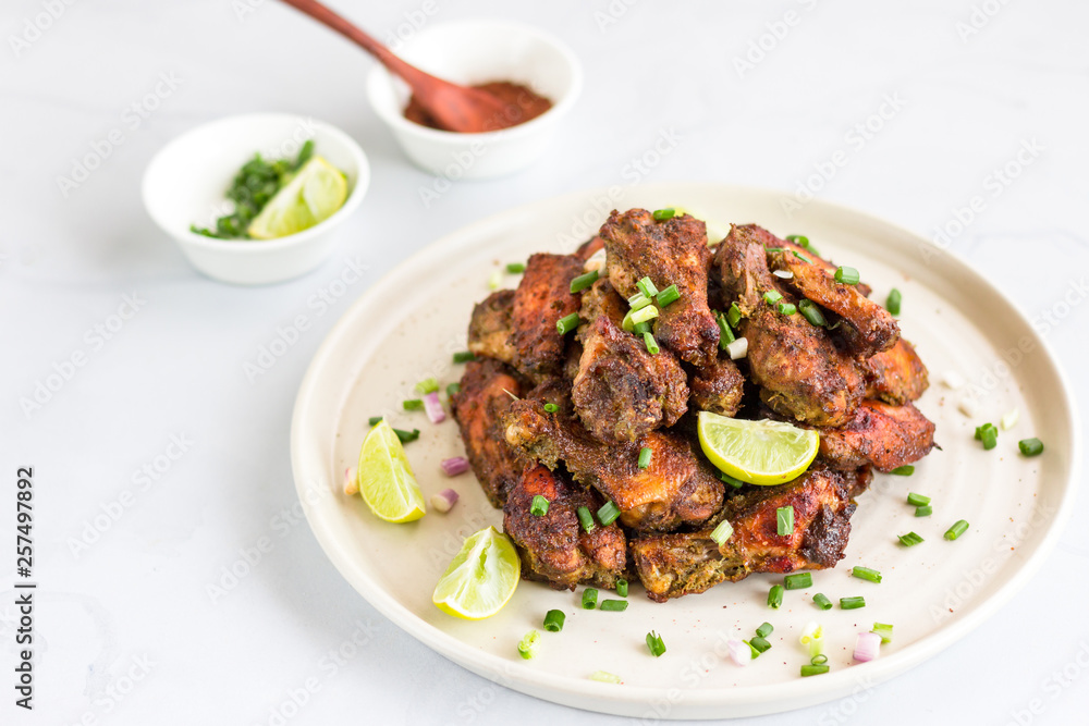 Jamaican Jerk Chicken Wings ona Plate Horizontal Photo. Caribbean Style Dry Rubbed Chicken Wings on White Background, Popular Chicken Appetizer.