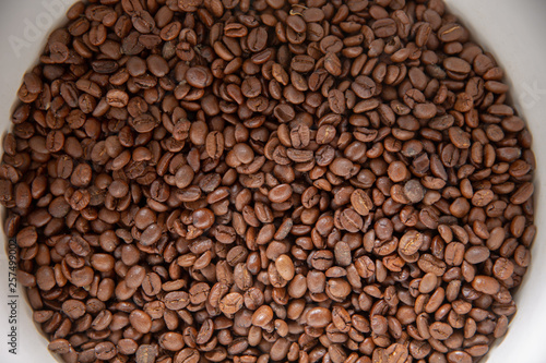 Coffee seeds in a big ceramic mug on a table background. Heap of coffee beans in cup.