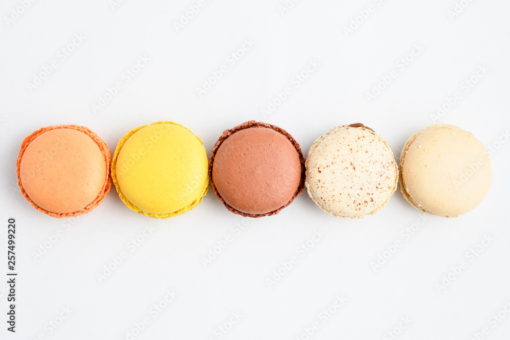 Close up of a row of five sweet French macarons with different aromas, isolated on white, flavours of orange, lemon, caramel, chocolate, coconut and vanilla, pastel colors Close up of a row of five sweet French macarons with different aromas, isolated on white, flavours of orange, lemon, caramel, chocolate, coconut and vanilla, pastel colors