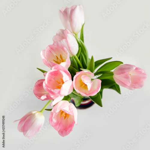 Wedding mockup with pink paper list and tulip flowers on blue table top view. Beautiful floral. Flat lay style.