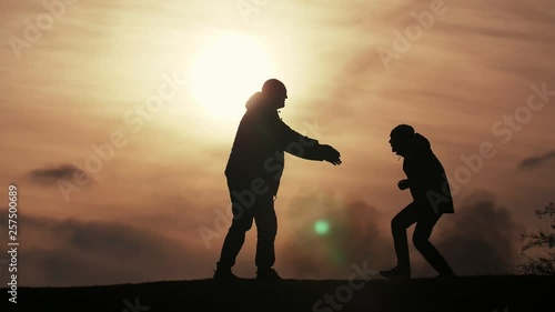 Happy father catching his jumping son in a field at dark sunset in spring in slo-mo  