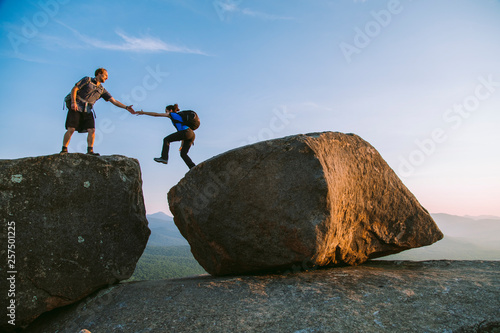 Man helping woman across boulder, Pitchoff?Mountain, Adirondack Mountains, New York State, USA photo