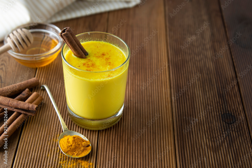 Turmeric Golden Milk. Healthy drink made with turmeric honey and cinnamon. Remedy for many diseases. Rustic wooden background. Turmeric Golden Milk. Healthy drink made with turmeric honey and cinnamon. Remedy for many diseases. Rustic wooden background.