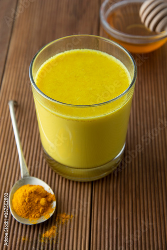 Turmeric Golden Milk. Healthy drink made with turmeric and honey. Remedy for many diseases. Rustic wooden background.