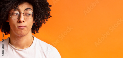 Black millennial man looking skeptically aside at empty space