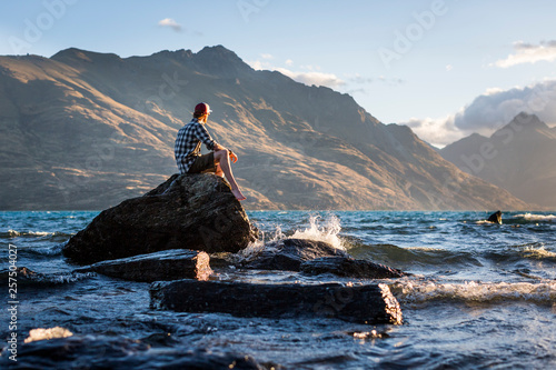 Man sitting on rock in Lake Wakatipu, Otago, New Zealand photo