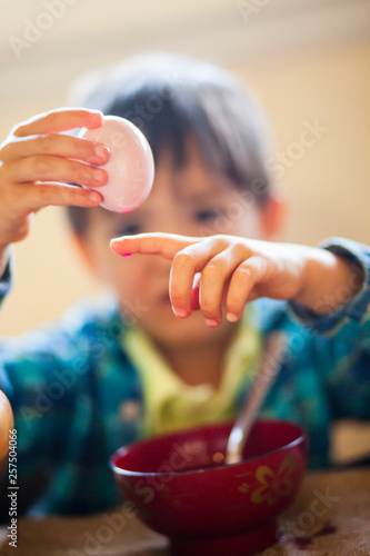 A four year old Japanese American boy dyes (colors) organic Easter eggs with natural food coloring. photo