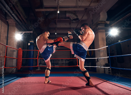 Two young sportsmen kickboxers training kickboxing in the ring at the sport club