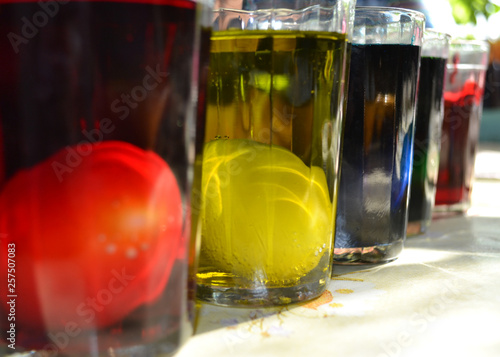 Easter eggs in glass cups and painted in red, yellow, blue and green