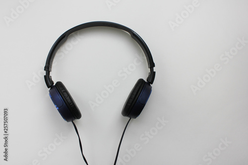 Black headphones isolated on grey empty background. Music listening device top view image of modern electronic gadget with microphone, volume and cord. New portable headphones with blank copy space
