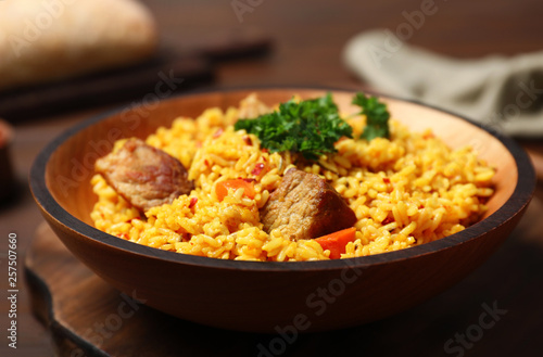 Plate with rice pilaf and meat on wooden table
