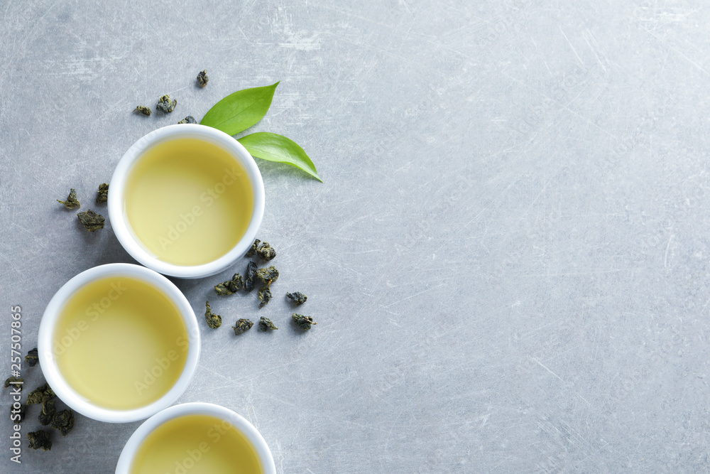 Cups of Tie Guan Yin oolong and tea leaves on grey background, top view with space for text Cups of Tie Guan Yin oolong and tea leaves on grey background, top view with space for text