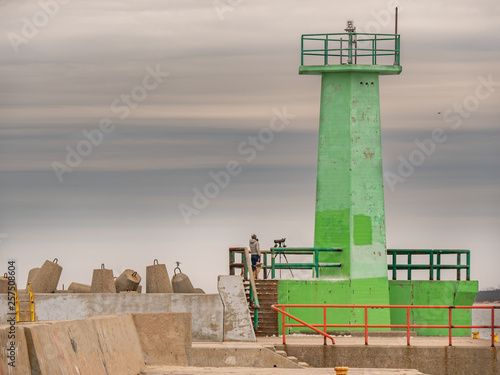 Obraz na płótnie Green lighthouse at the entrance to the harbour w salonie