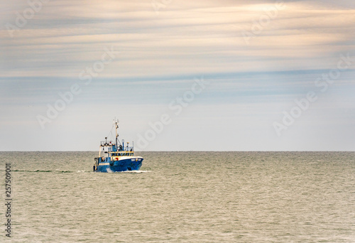Obraz na płótnie Small single fishing boat at the open sea with scenic sky. w salonie