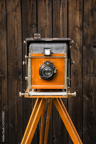 An old large format camera on a wooden tripod. photo