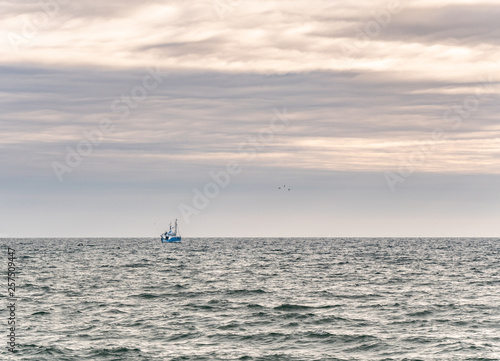 Obraz na płótnie Small single fishing boat at the open sea with scenic sky. w salonie