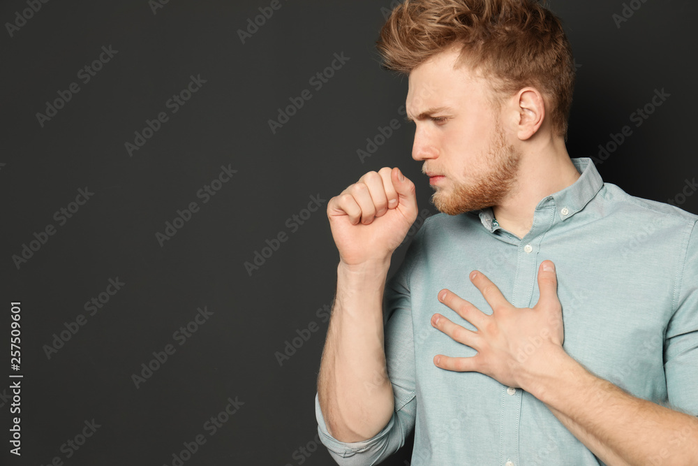 Handsome young man coughing against dark background. Space for text Handsome young man coughing against dark background. Space for text