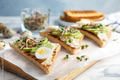 Tasty toasts with avocado, quail egg and chia seeds served on board