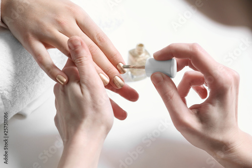 Manicurist painting client's nails with polish in salon, closeup