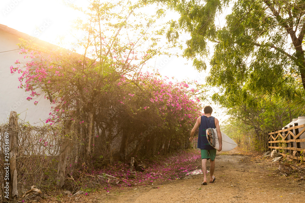 A Male Surfer Walks Home From The Beach At Popoyo Beach, Nicaragua A Male Surfer Walks Home From The Beach At Popoyo Beach, Nicaragua
