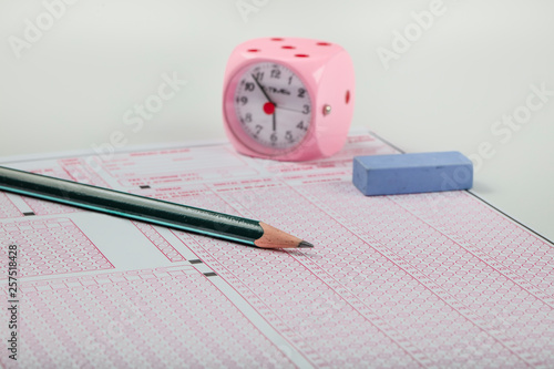 high school or university student hands taking exams, writing examination on paper answer sheet optical form of standardized test on desk doing final exam in classroom. Education literacy concept. 